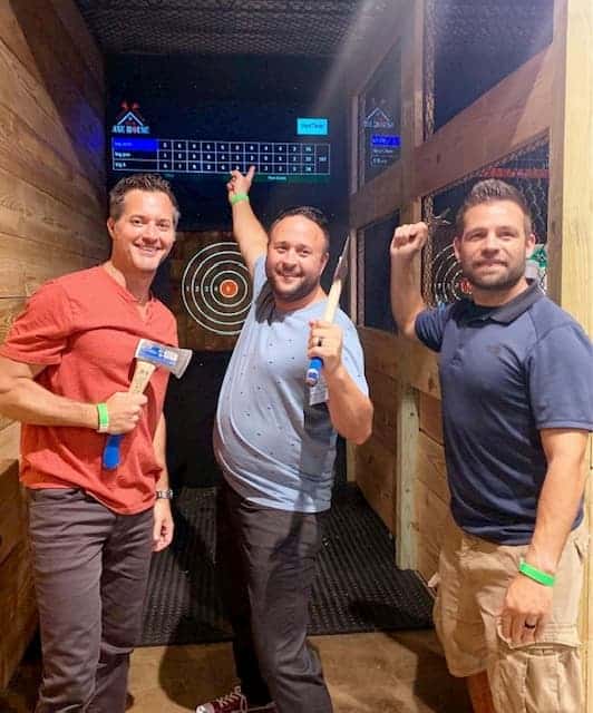 3 guys in front of axe throwing lane at bachelor party